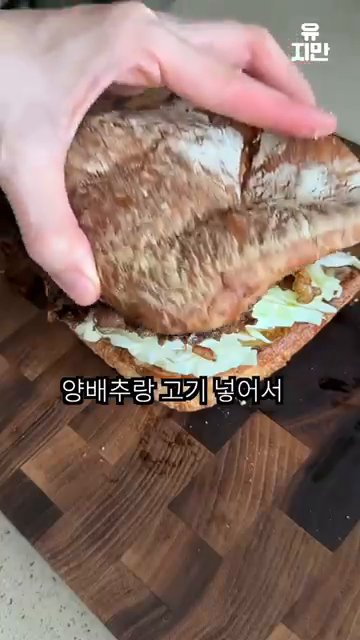 모든 재료가 잘 들어간 샌드위치를 한 입 크게 베어물어 맛을 즐깁니다.