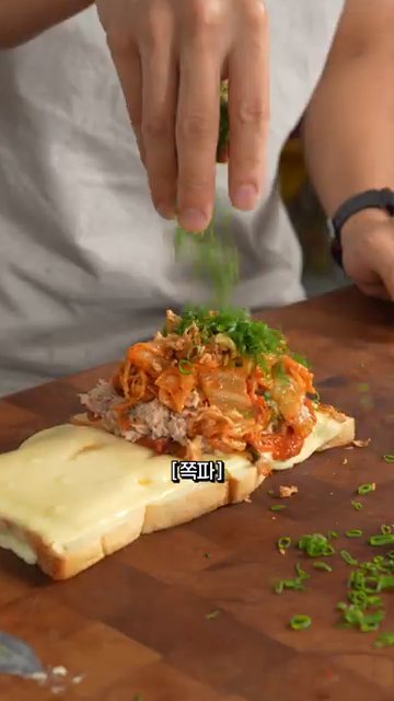 식빵 한쪽 면에 김치 참치 혼합물을 올리고, 녹인 치즈를 얹습니다.