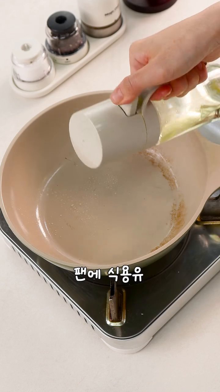 팬에 식용유를 살짝 두르고 만두를 올린 후, 물 반컵과 밀가루 반스푼, 식용유 한스푼을 섞어 부어줍니다.